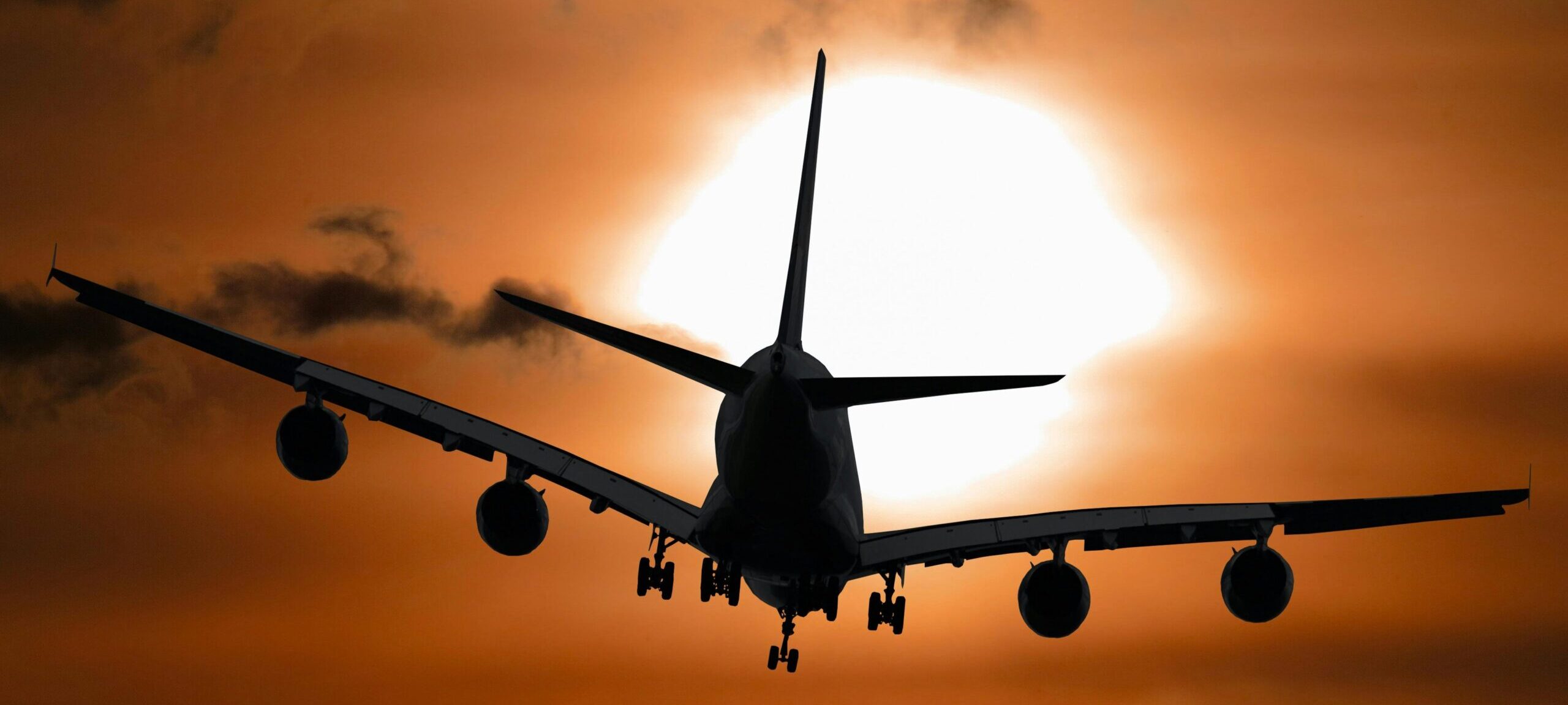 Dramatic silhouette of an airplane flying against a vibrant sunset sky.